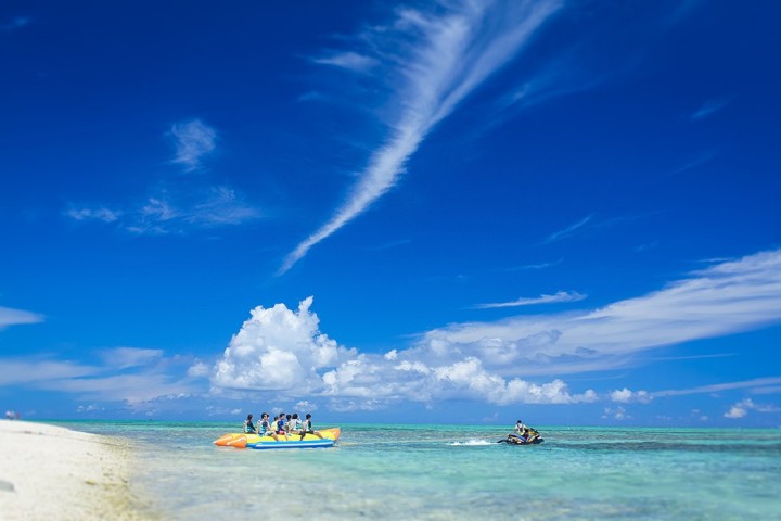 沖縄の青い海でバナナボートをする観光客